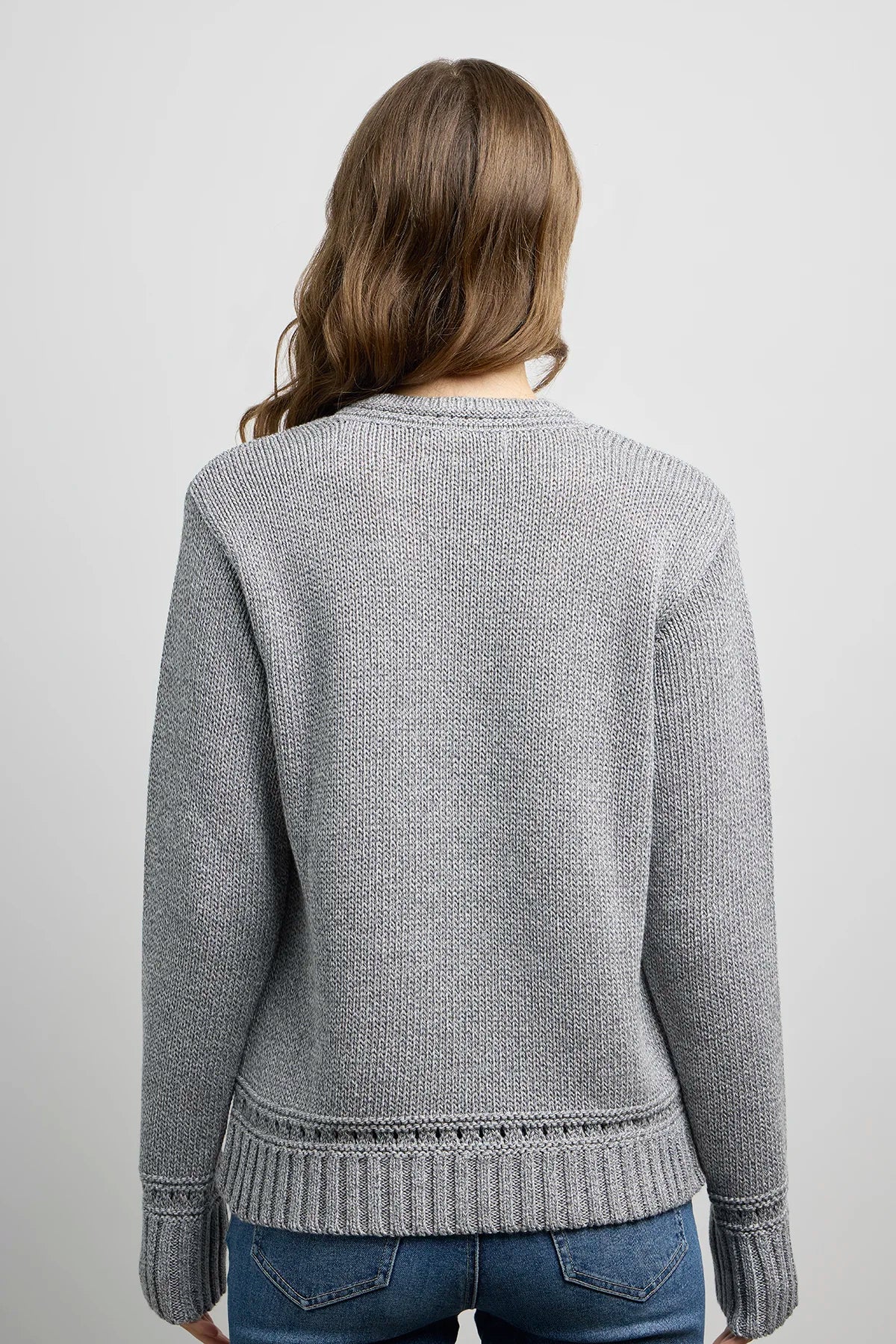 Back view of a grey knit sweater with ribbed hem and cuffs, featuring a subtle decorative stitch detail near the waistband.