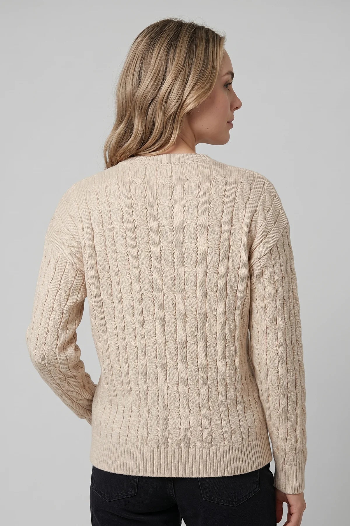 Back view of cream cable knit sweater featuring classic textured knit detailing and ribbed hem.