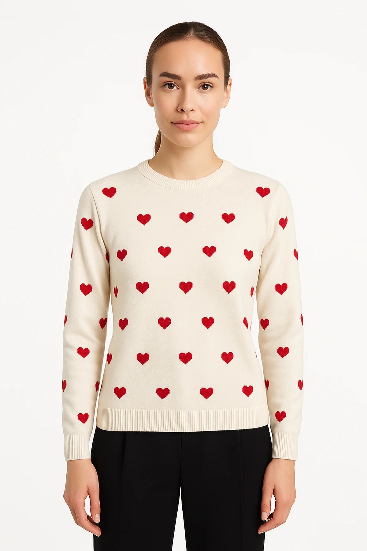 Woman wearing a natural-colored sweater with a red heart pattern, long sleeves, and a ribbed hem, standing against a white background.