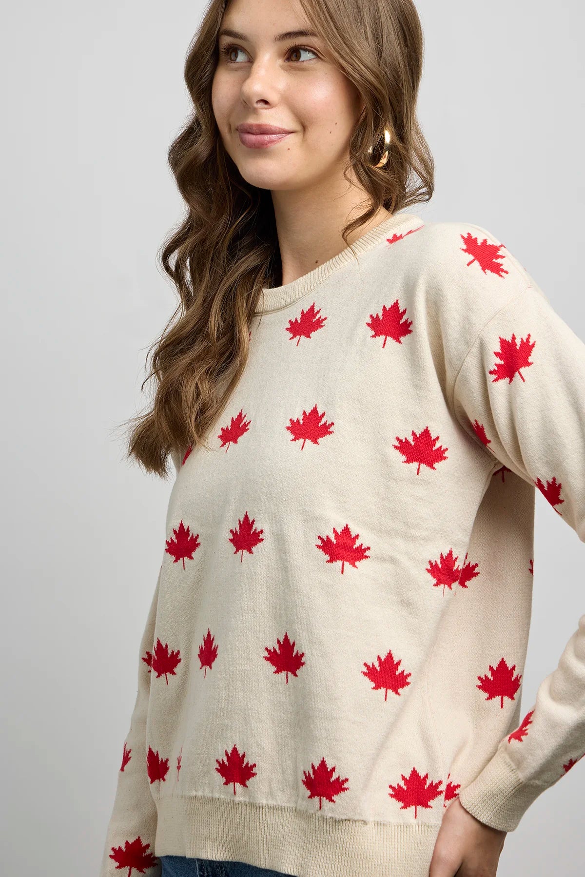 Side view of a knit sweater featuring an all-over maple leaf pattern with ribbed crewneck, cuffs, and hem.