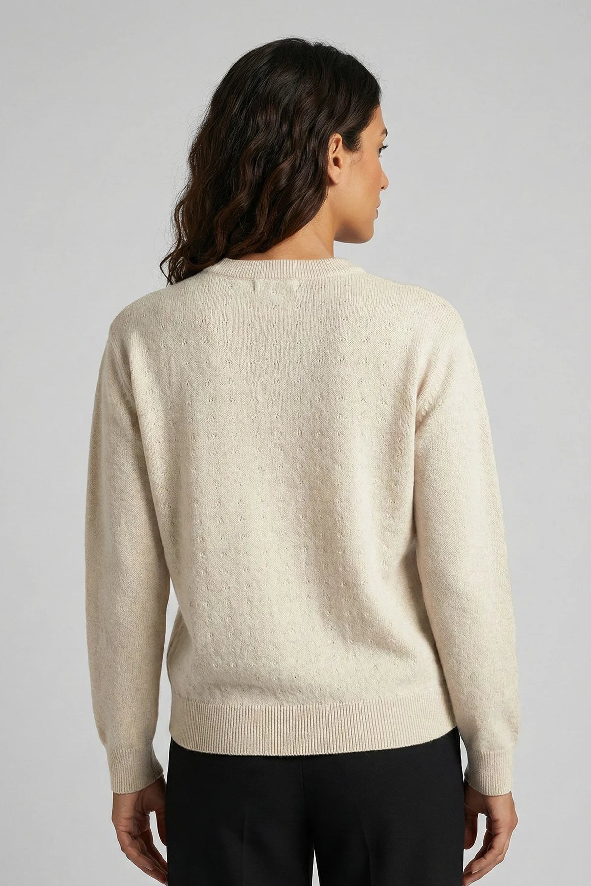 Woman wearing a beige sweater against a plain background