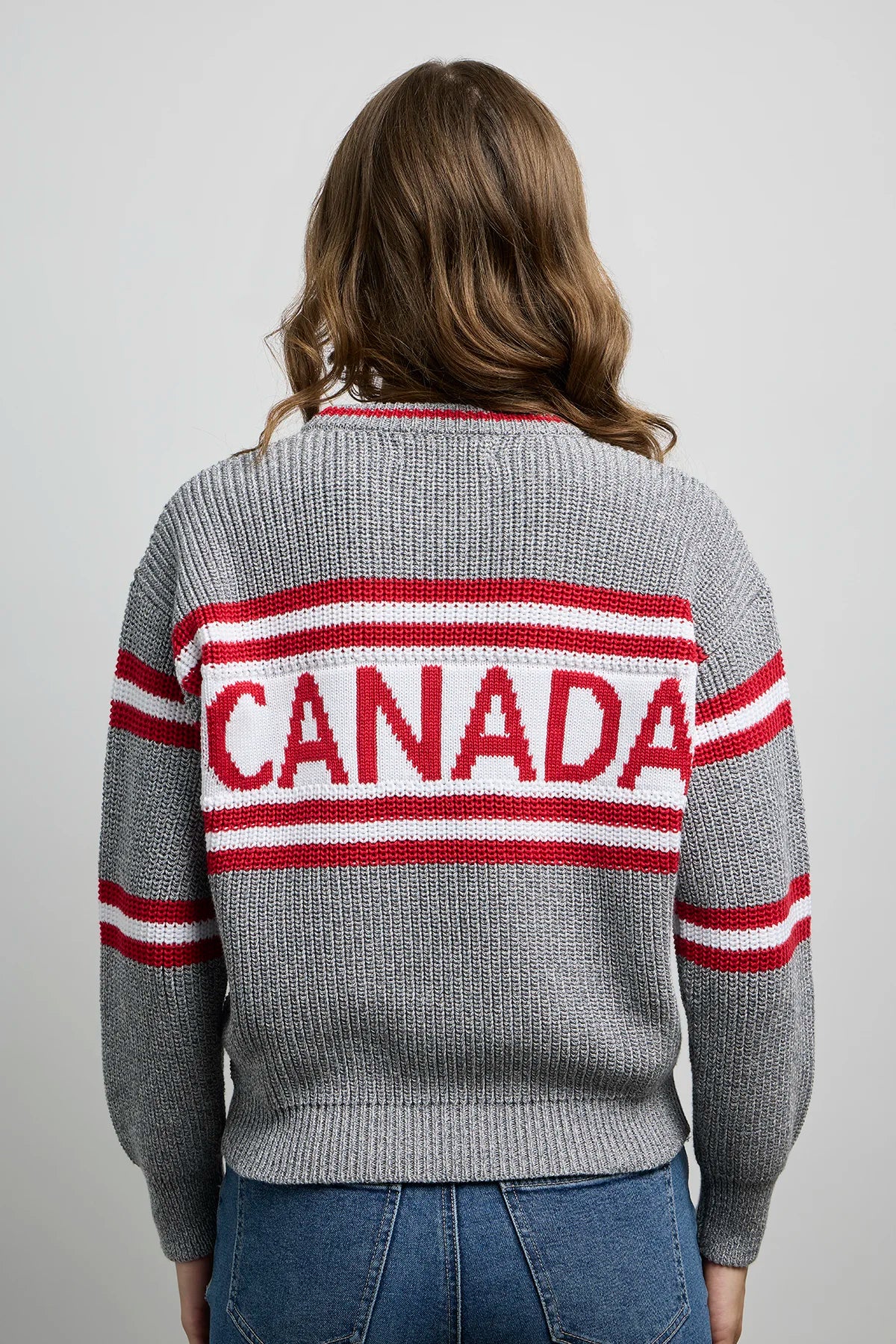 Person wearing a grey sweater with “CANADA” printed in red and white on the back.