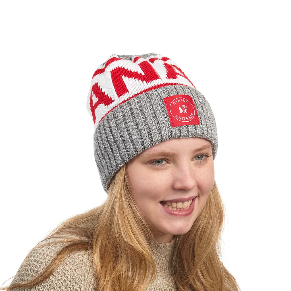 Person wearing a gray and red knit beanie with a visible Canada Knitwear logo on a white background