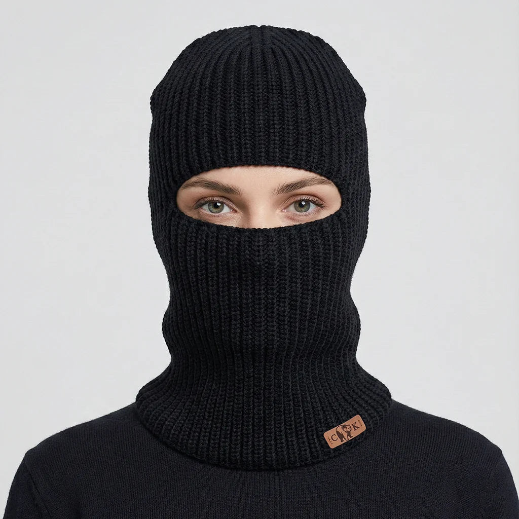 Person wearing a black knit balaclava with a Canada Knitwear logo on a light gray background
