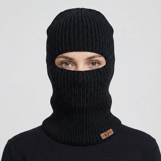 Person wearing a black knit balaclava with a Canada Knitwear logo on a light gray background