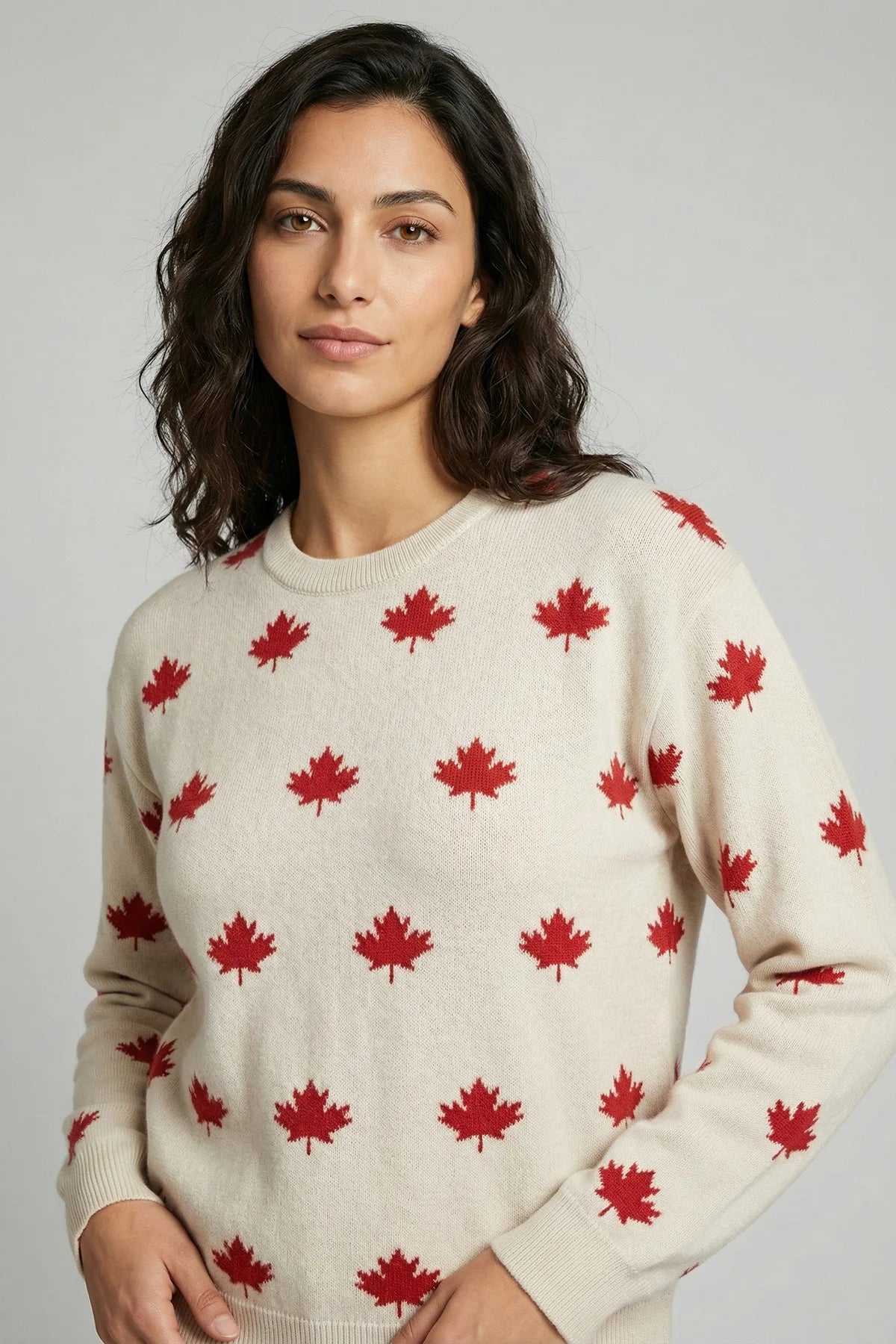 Woman wearing a cream sweater with red maple leaf pattern against a gray background