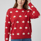 Woman wearing a red sweater with white maple leaf patterns on a plain background