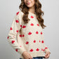 Front view of knit sweater with maple leaf pattern, long sleeves, ribbed crewneck, cuffs, and hem.