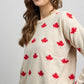 Side view of a knit sweater featuring an all-over maple leaf pattern with ribbed crewneck, cuffs, and hem.
