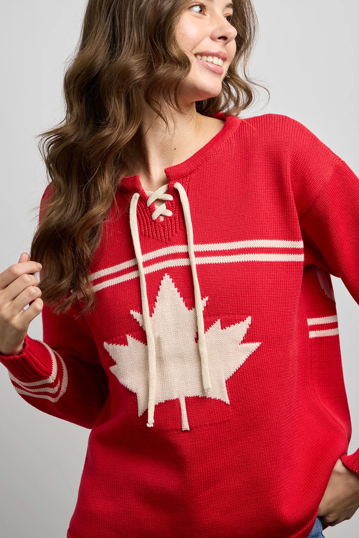Red hockey sweater with lace-up neckline, white maple leaf crest on the chest, and horizontal stripe detailing on the sleeves and torso.
