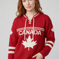 Woman wearing red Legacy Hockey Sweater with white maple leaf graphic, CANADA lettering, and lace-up neckline.