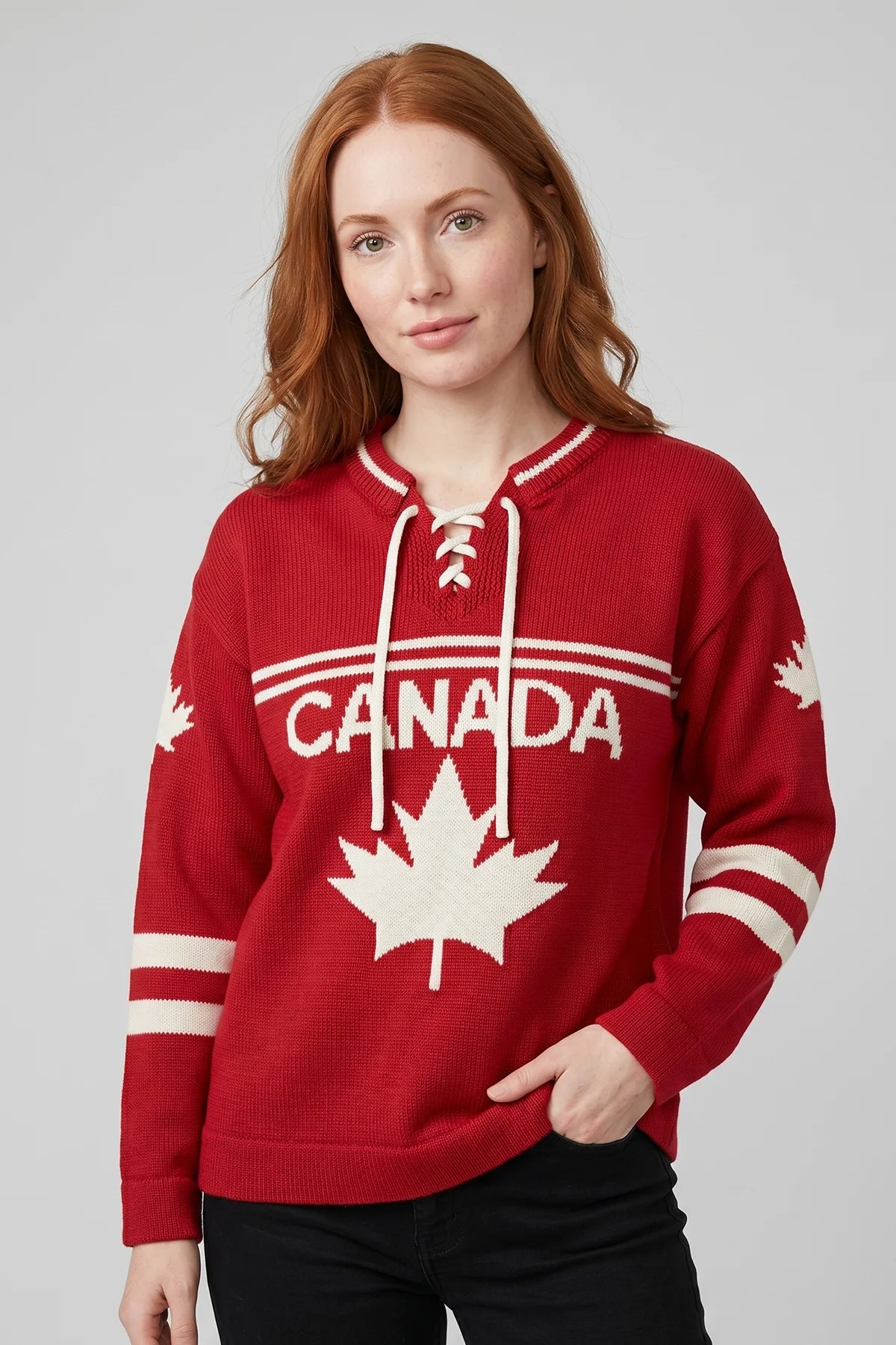 Woman wearing red Legacy Hockey Sweater with white maple leaf graphic, CANADA lettering, and lace-up neckline.
