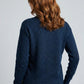 Woman wearing a navy blue patterned sweater against a gray background