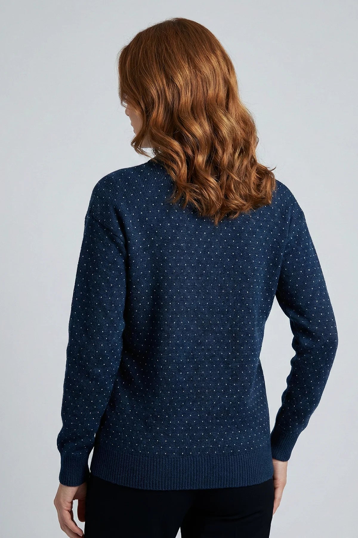 Woman wearing a navy blue patterned sweater against a gray background