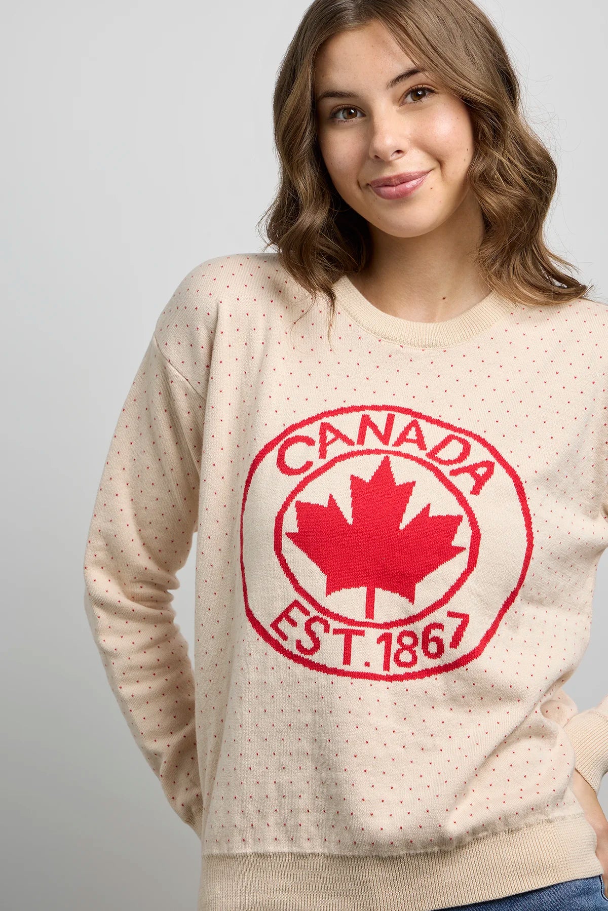 Front close-up of Sweater 1867 with dotted knit pattern, ribbed neckline, and bold red maple leaf crest featuring Canada EST. 1867 text.