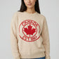 Woman wearing a beige sweater with a red 'Canada Est. 1867' design on a plain background