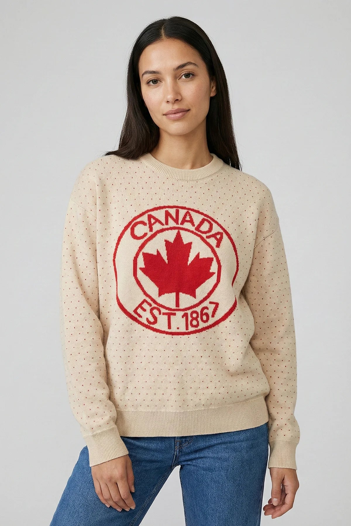 Woman wearing a beige sweater with a red 'Canada Est. 1867' design on a plain background