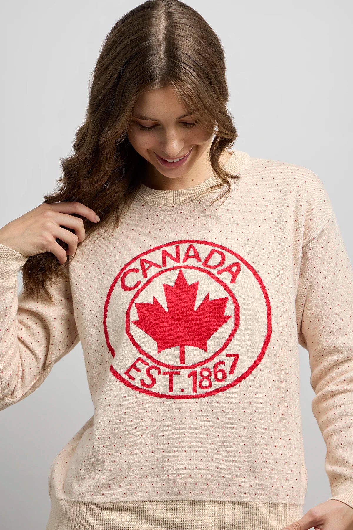 Front view of Sweater 1867 in knit fabric with dotted detailing, ribbed crewneck, and bold red maple leaf crest featuring Canada EST. 1867 text.