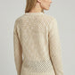 Woman wearing a beige textured knitted summer sweater against a plain background