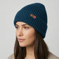 Woman wearing a blue knit beanie with a Canada Knitwear logo on a light gray background