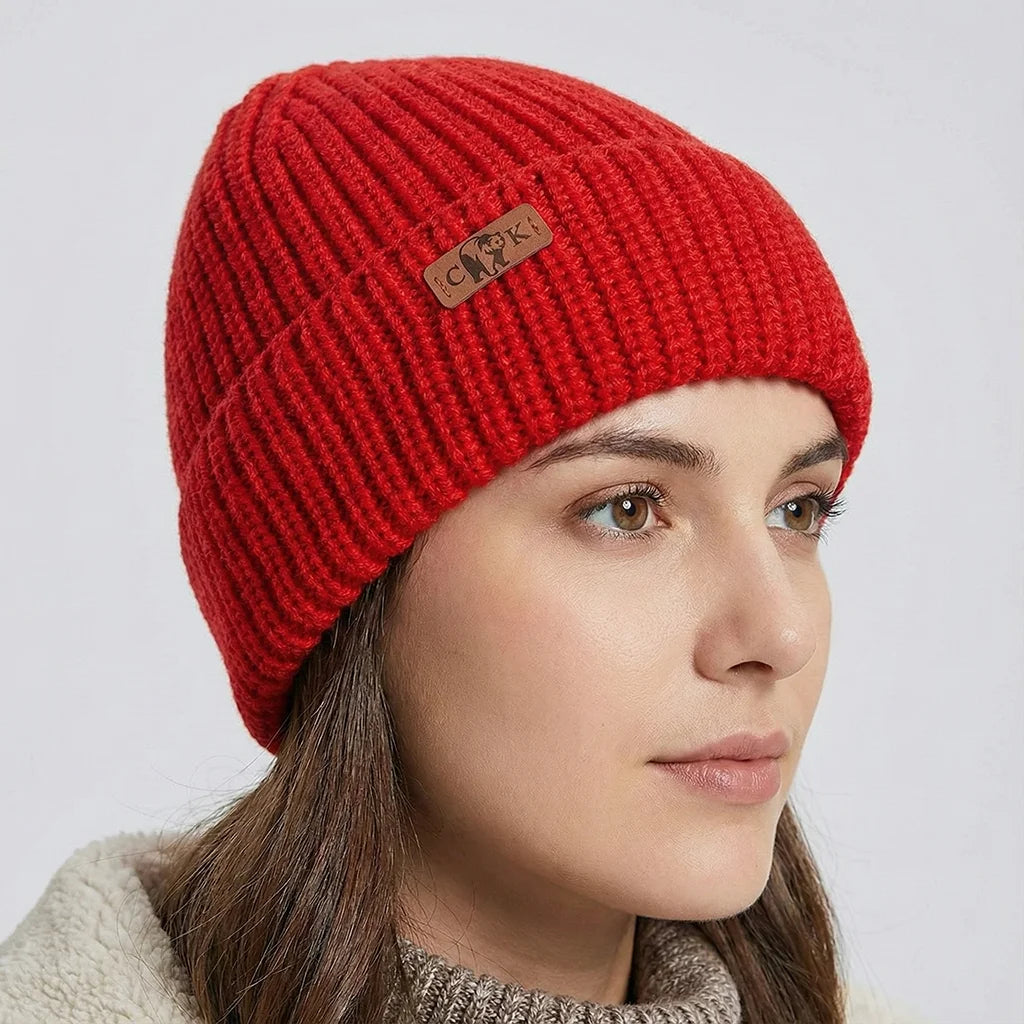 Person wearing a red knit beanie with a Canada Knitwear logo on a light gray background